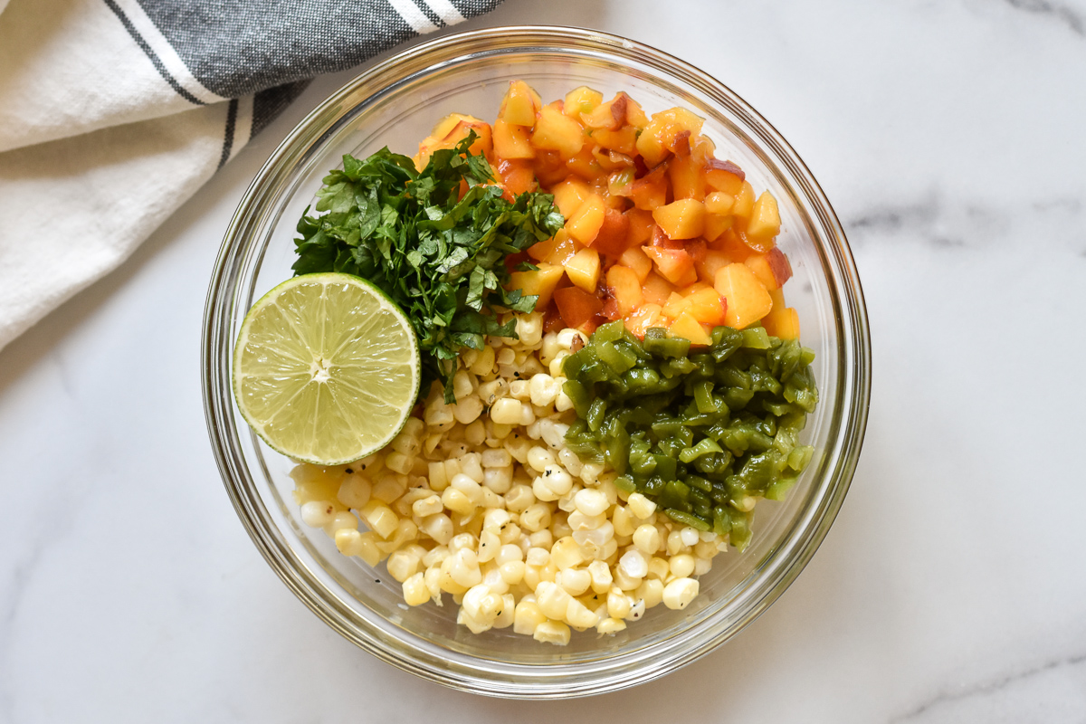 peaches, hatch green chiles, corn, lime and cilantro in a bowl