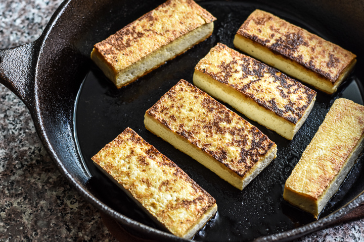 tofu browning in a cast iron skillet