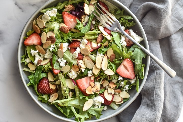 salad with strawberries, goat cheese and sliced almonds in a bowl