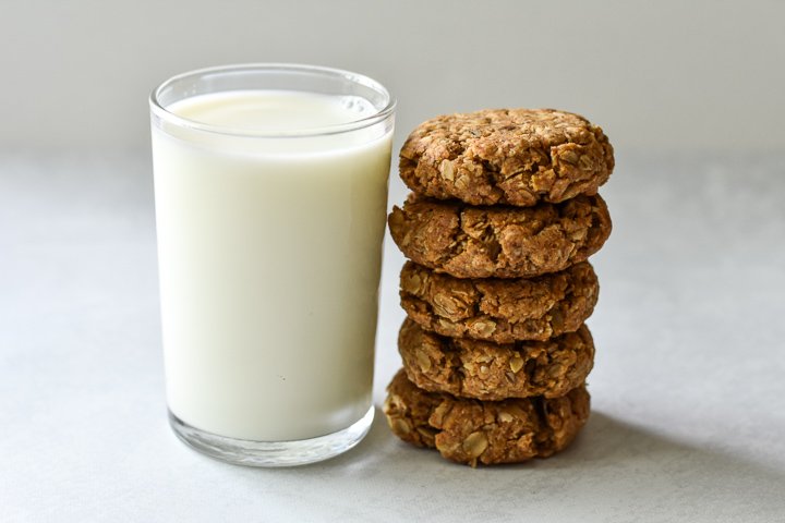 stack of vegan oatmeal cookies next to a glass of milk