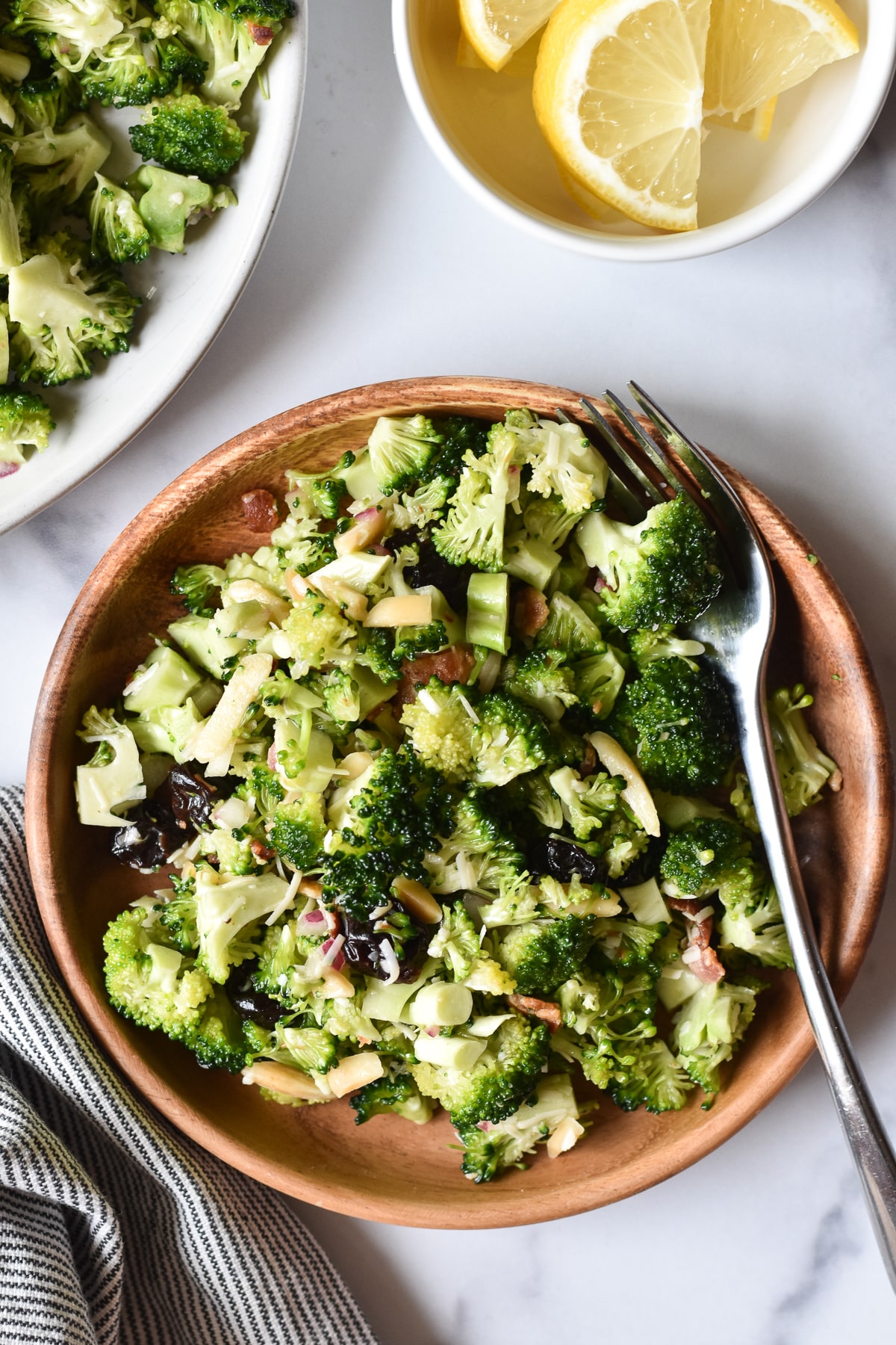 broccoli crunch salad on a small plate with lemon wedges