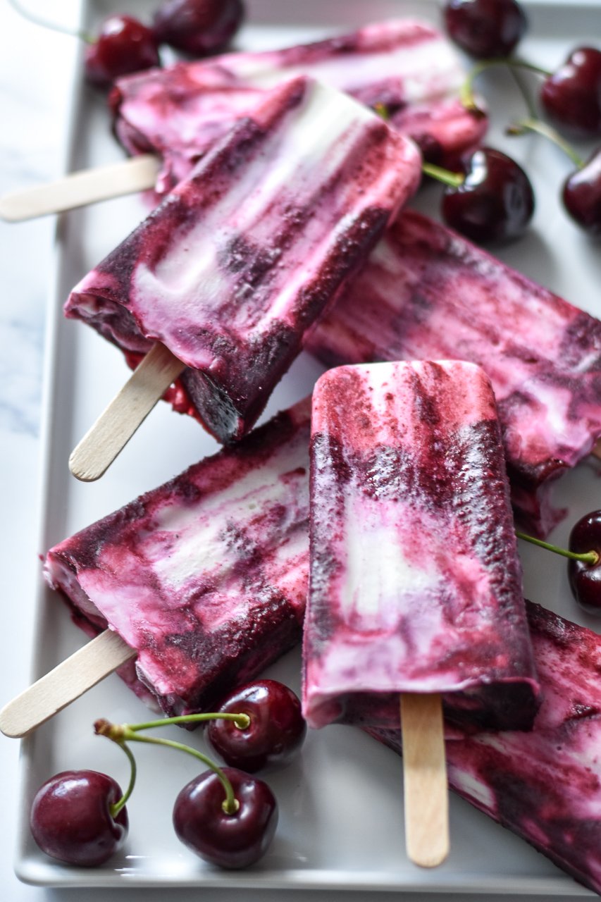 plate of cherry goat cheese paletas with fresh cherries scattered around