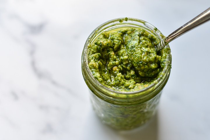 small jar of spinach almond pesto with a spoon