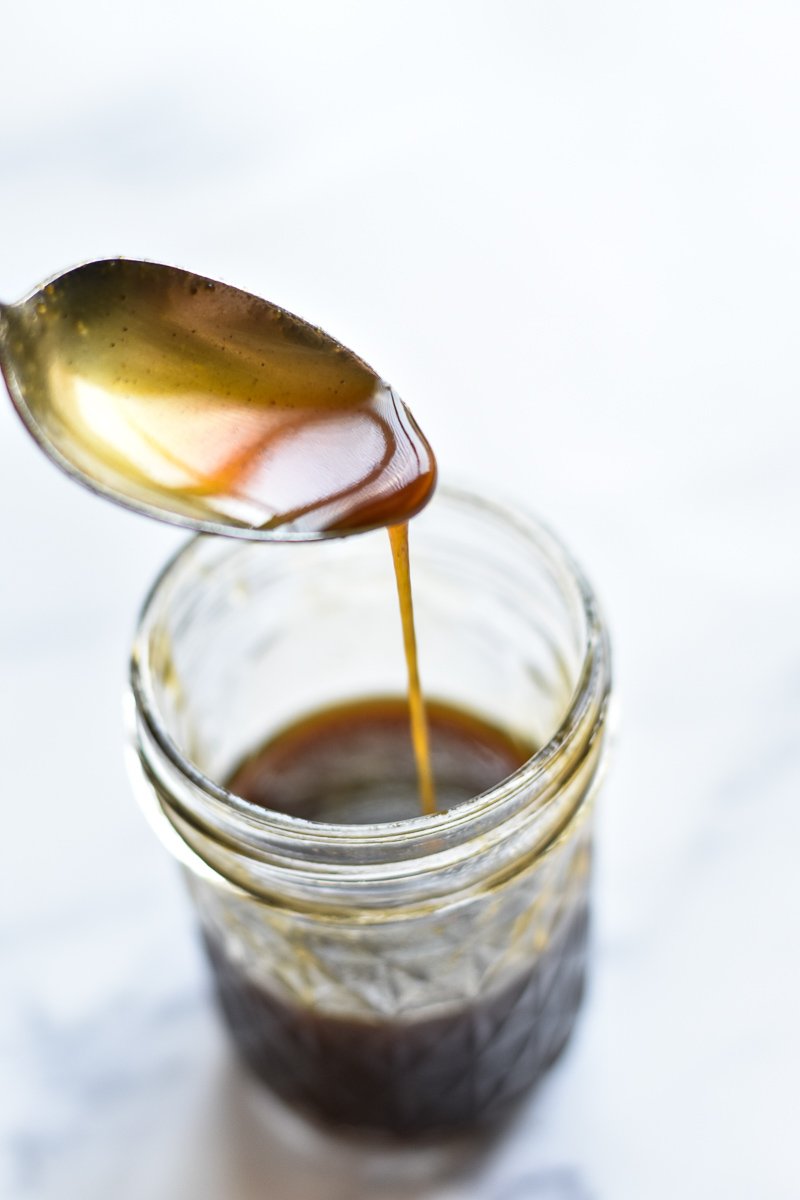 spoon drizzling pumpkin spice syrup into a jar