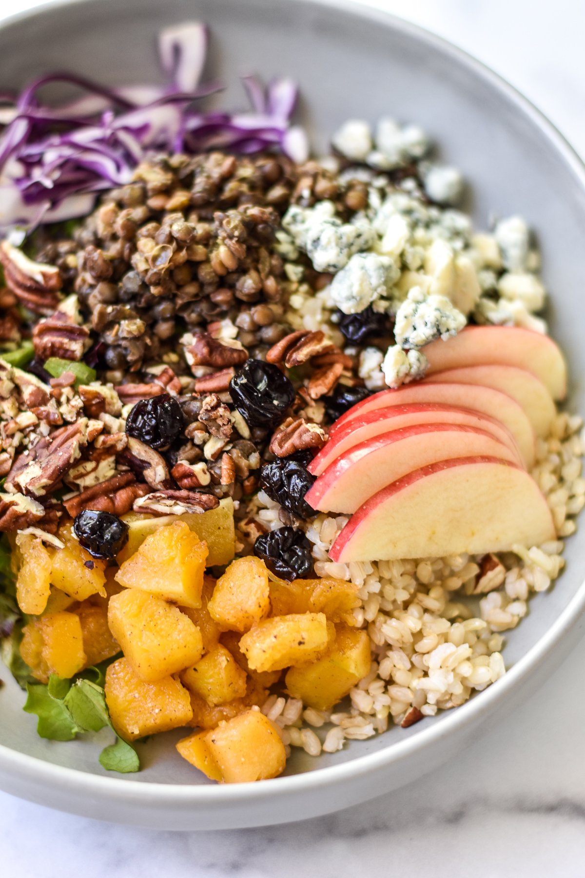 closeup of autumn grain bowl with apples and squash