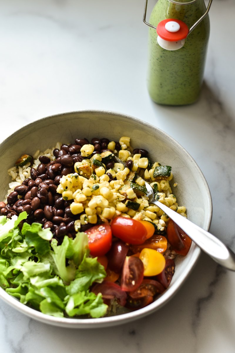 veggie burrito bowl with a bottle of green goddess dressing