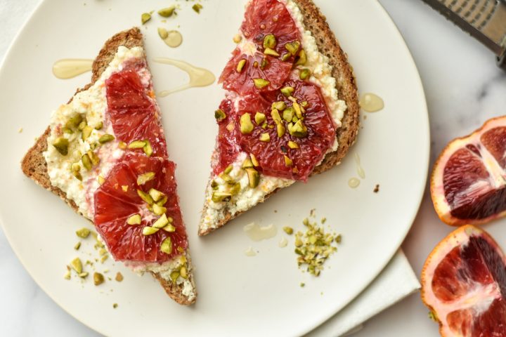 sliced toast with ricotta cheese, blood oranges and pistachios on a plate