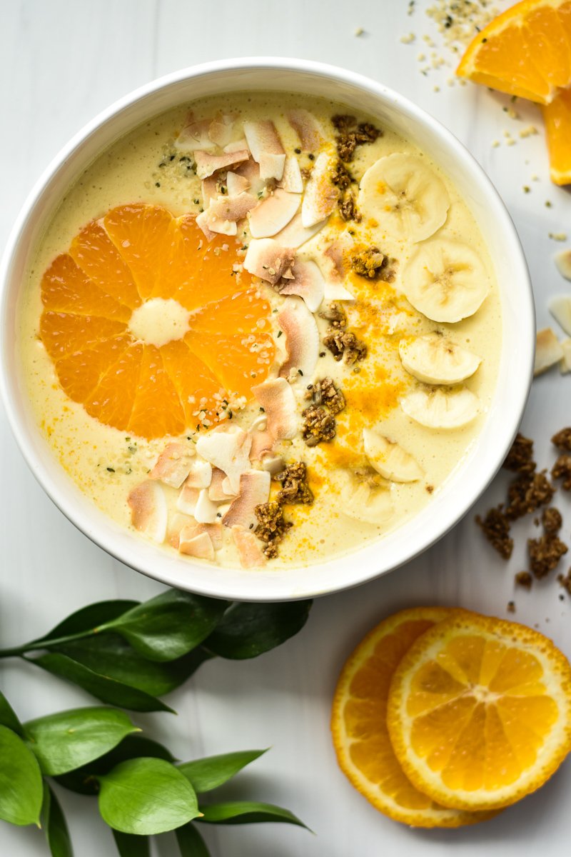 tropical smoothie bowl with greenery and orange slices