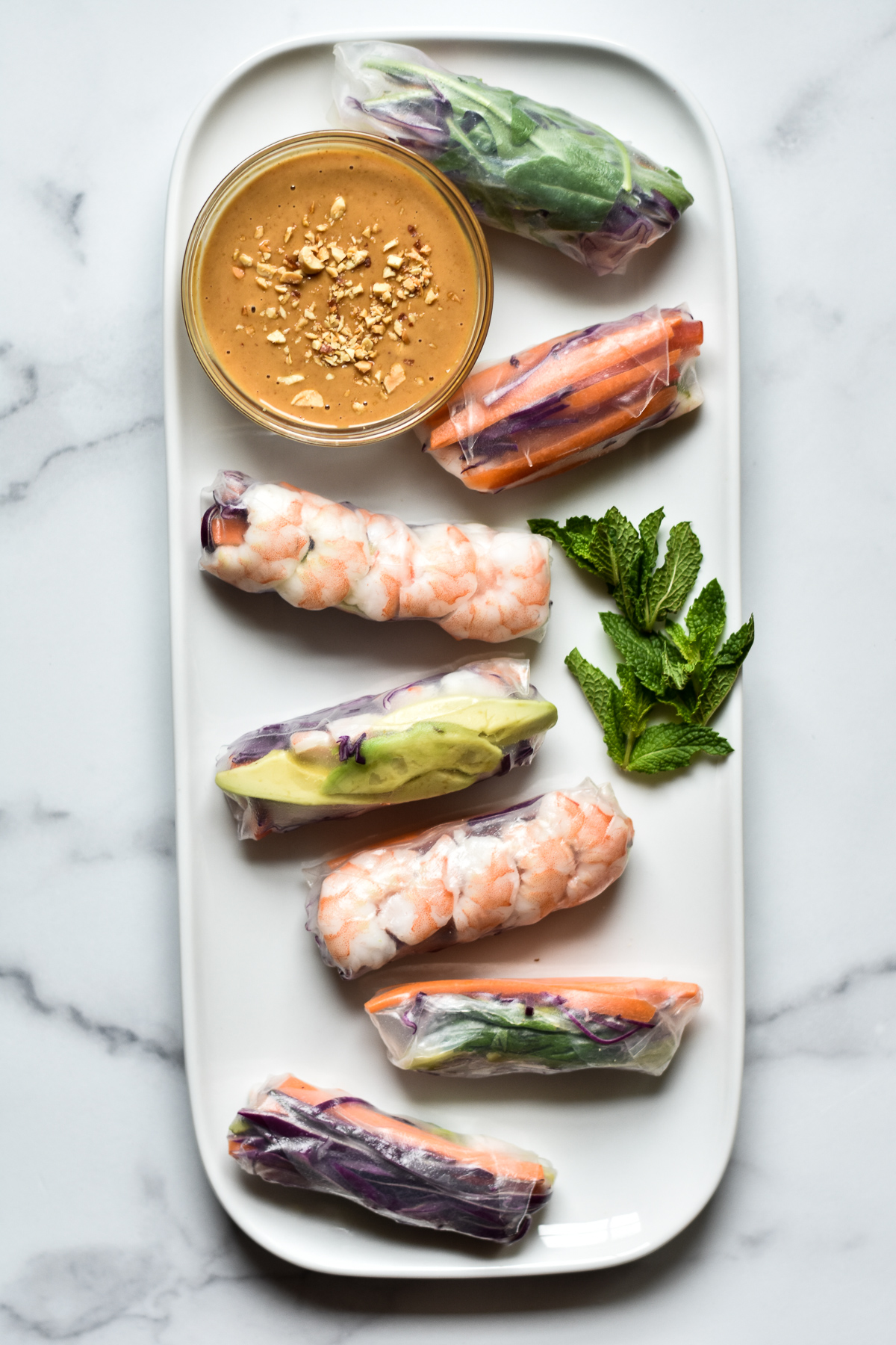 vegetable and shrimp summer rolls on a platter with dish of peanut sauce  and fresh mint