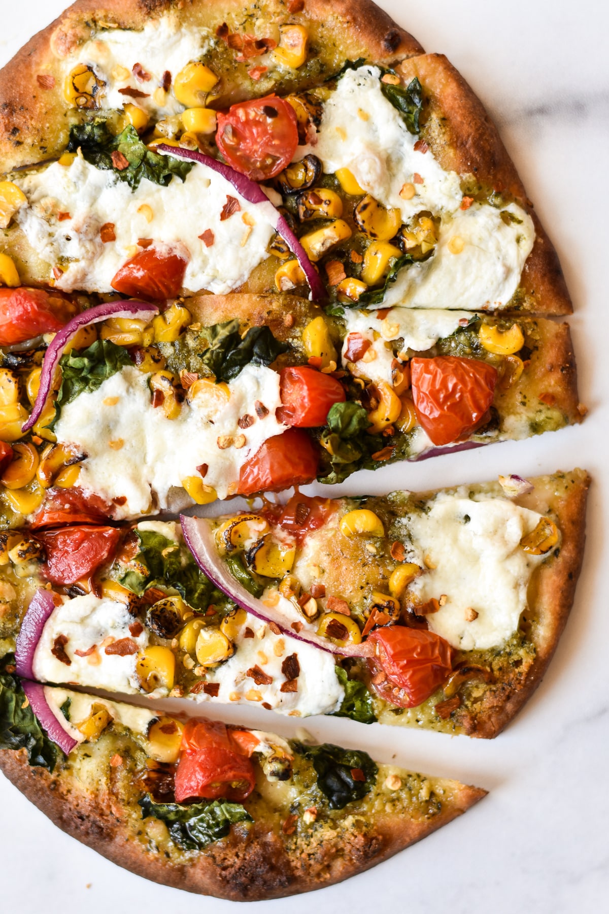 burrata pizza with summer vegetables on naan bread sliced into wedges