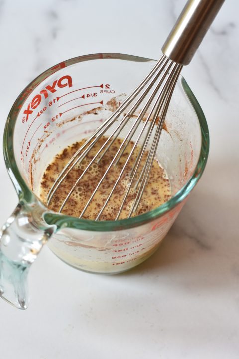 liquid measuring cup with eggs and milk and whisk