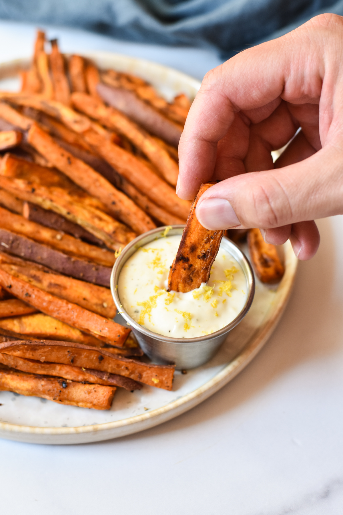 dipping a sweet potato fry in aioli sauce