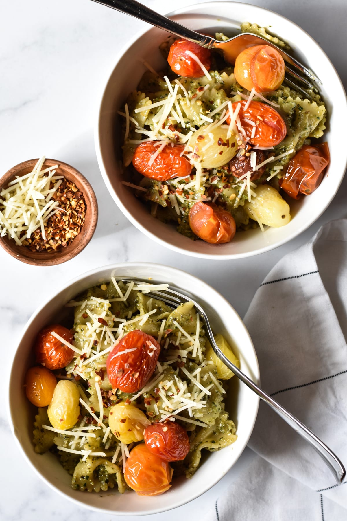 two bowls of pesto pasta with tomatoes