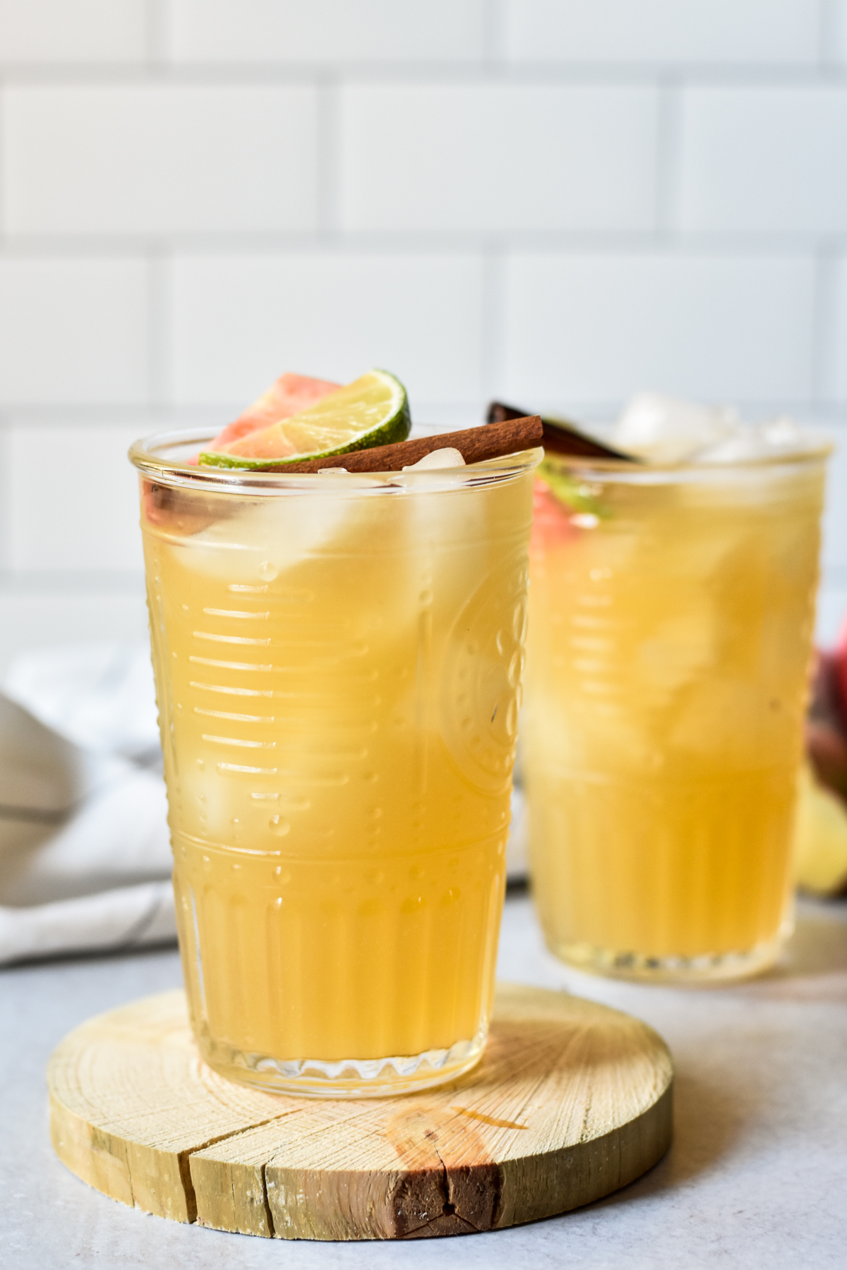 bourbon apple ginger fizz cocktails with lime and cinnamon stick