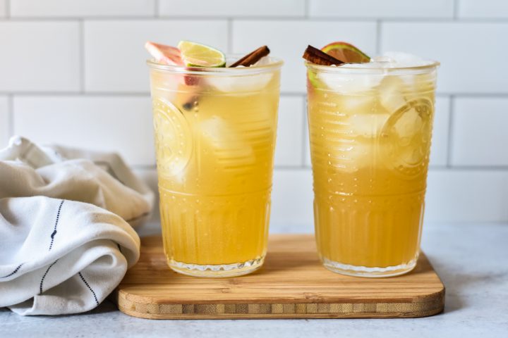 apple cider bourbon ginger cocktails in tall glasses on wood board