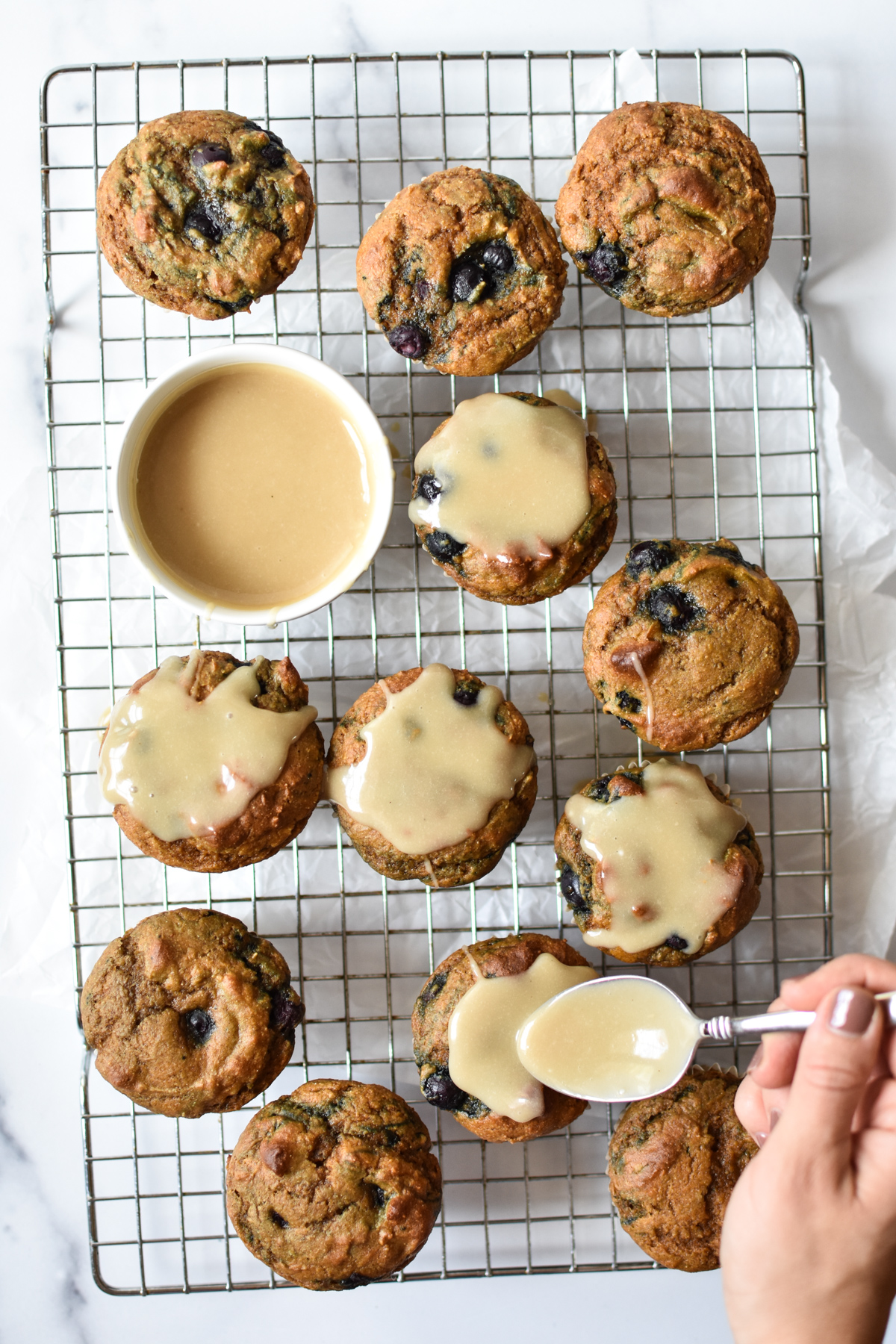 pumpkin blueberry muffins on a cooling rack with tahini glaze spooned on top