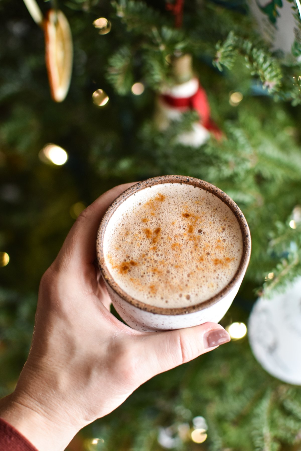 hot chocolate mug in front of a Christmas tree