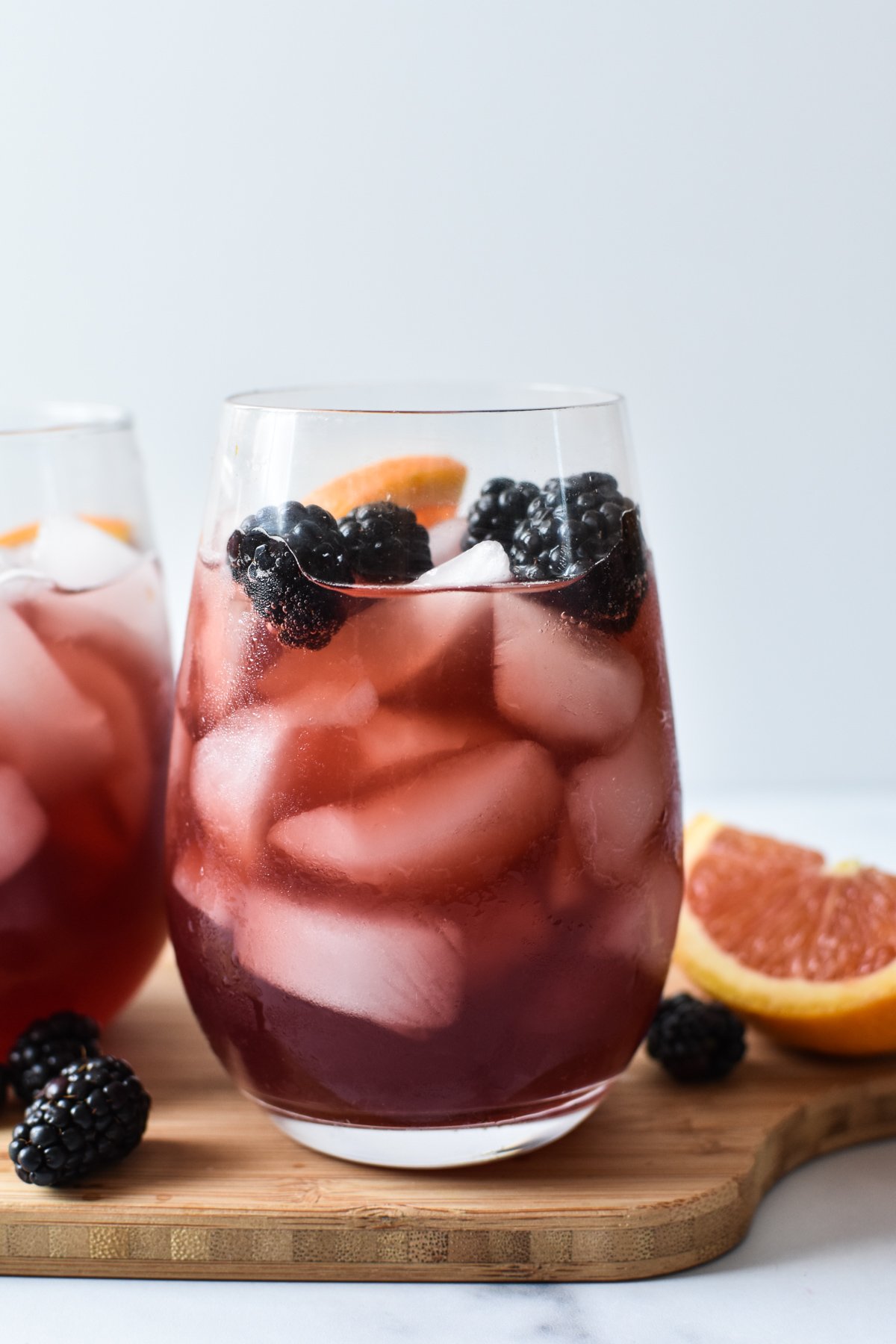 sangria mocktail in a stemless wine glass with blackberries and orange