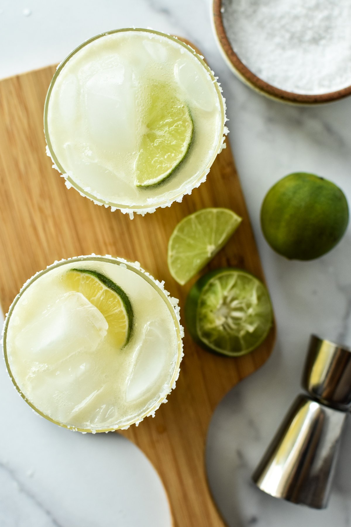 margarita mocktail in a glass with limes and jigger