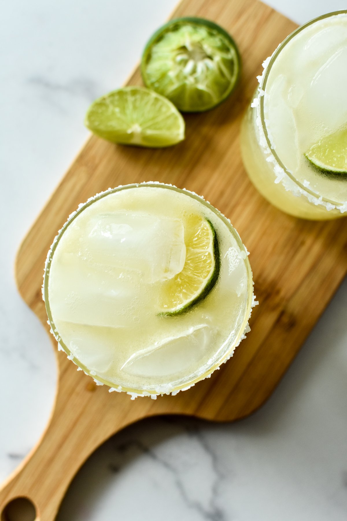 margarita mocktails on a wooden cutting board with limes