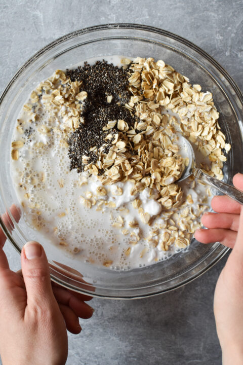 mixing overnight oats with coconut in a large bowl