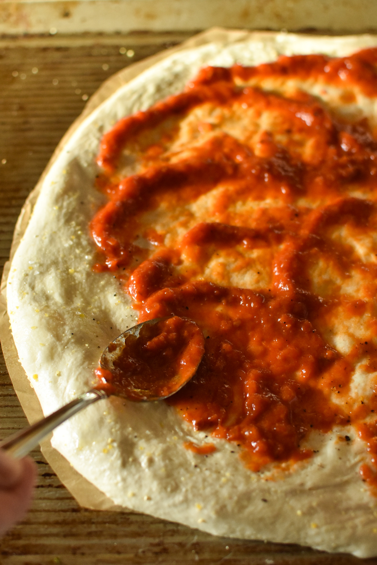 spreading sauce on pizza dough