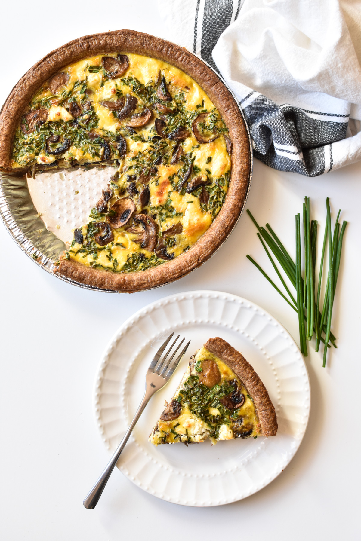 large mushroom chive quiche with a slice taken out of it