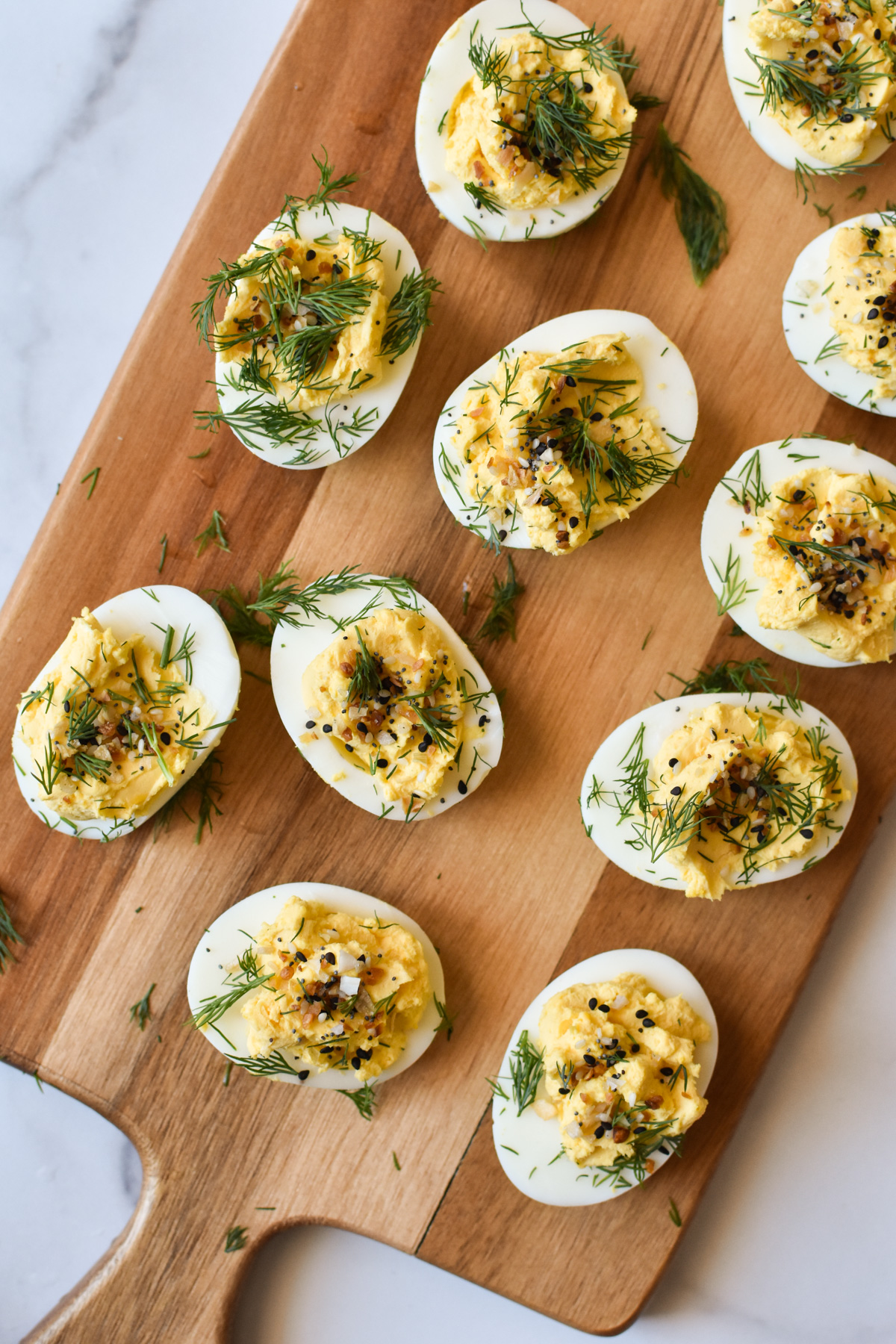 everything bagel deviled eggs with dill on a wood cutting board