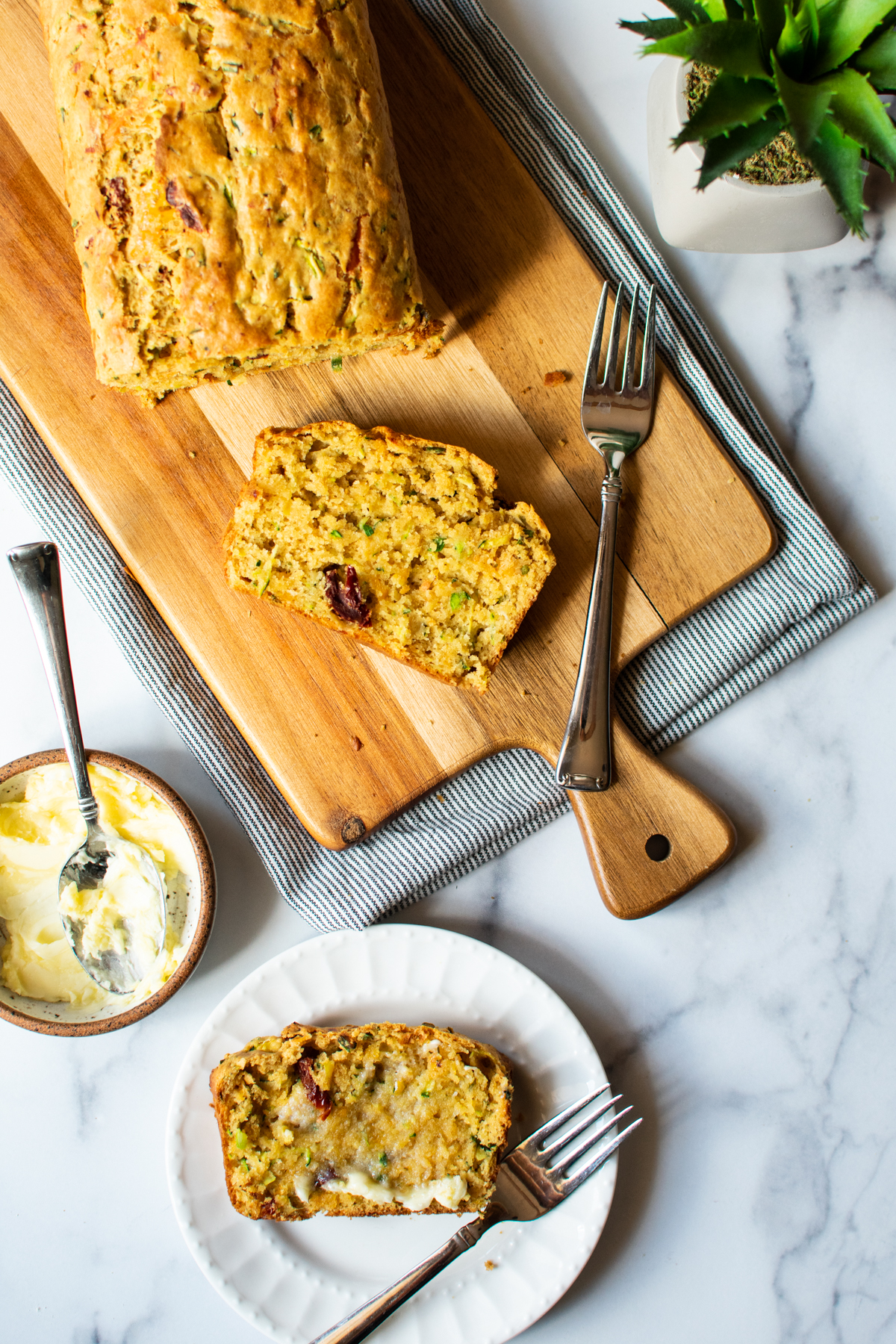 zucchini bread on a cutting board with butter on the side