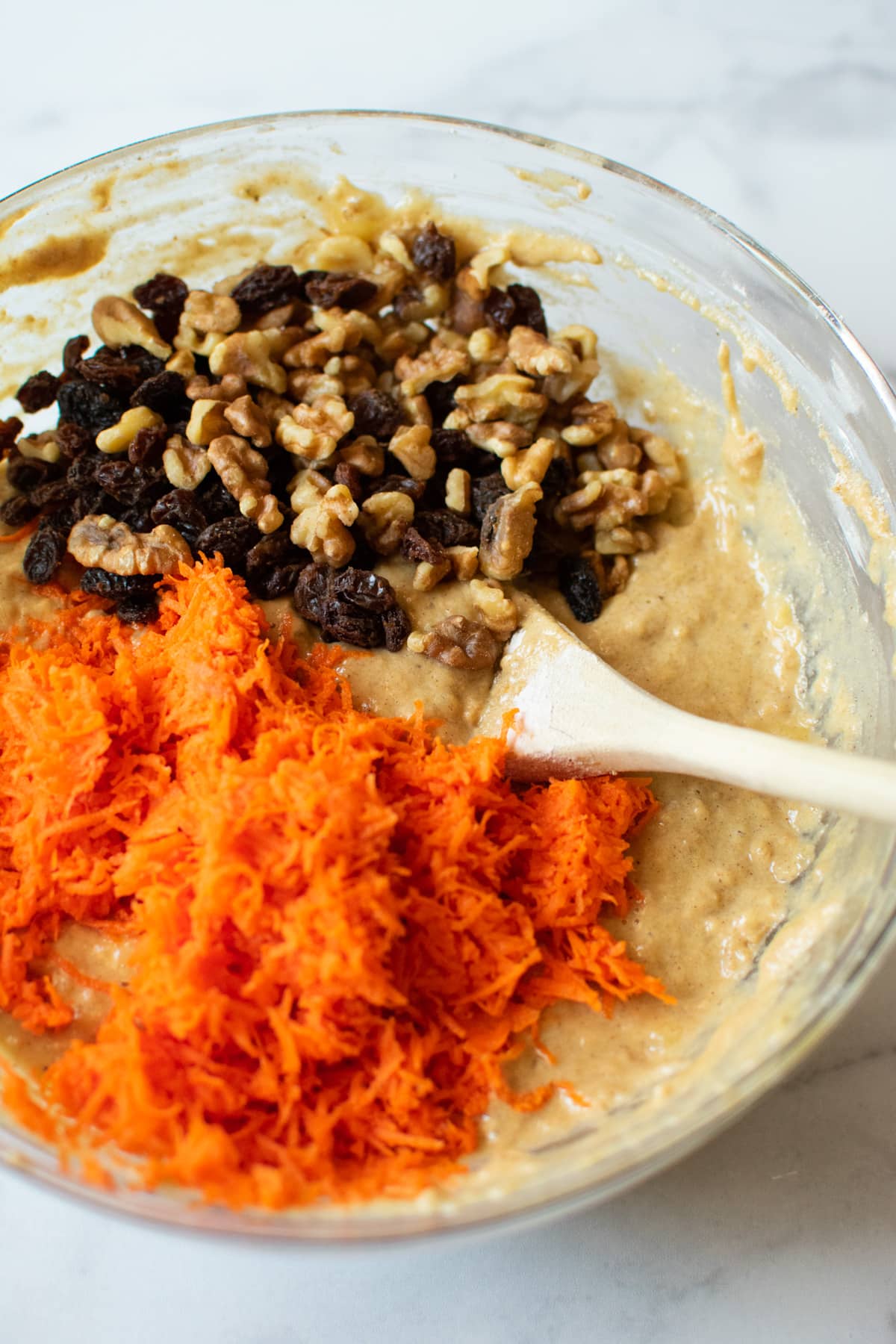 bowl of muffin batter with shredded carrots, raisins and walnuts