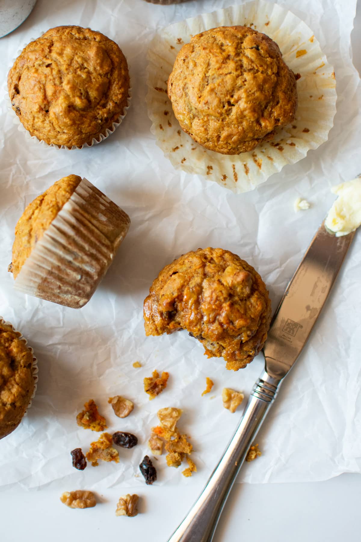 closeup photo of muffins with some walnuts and raisins scattered around