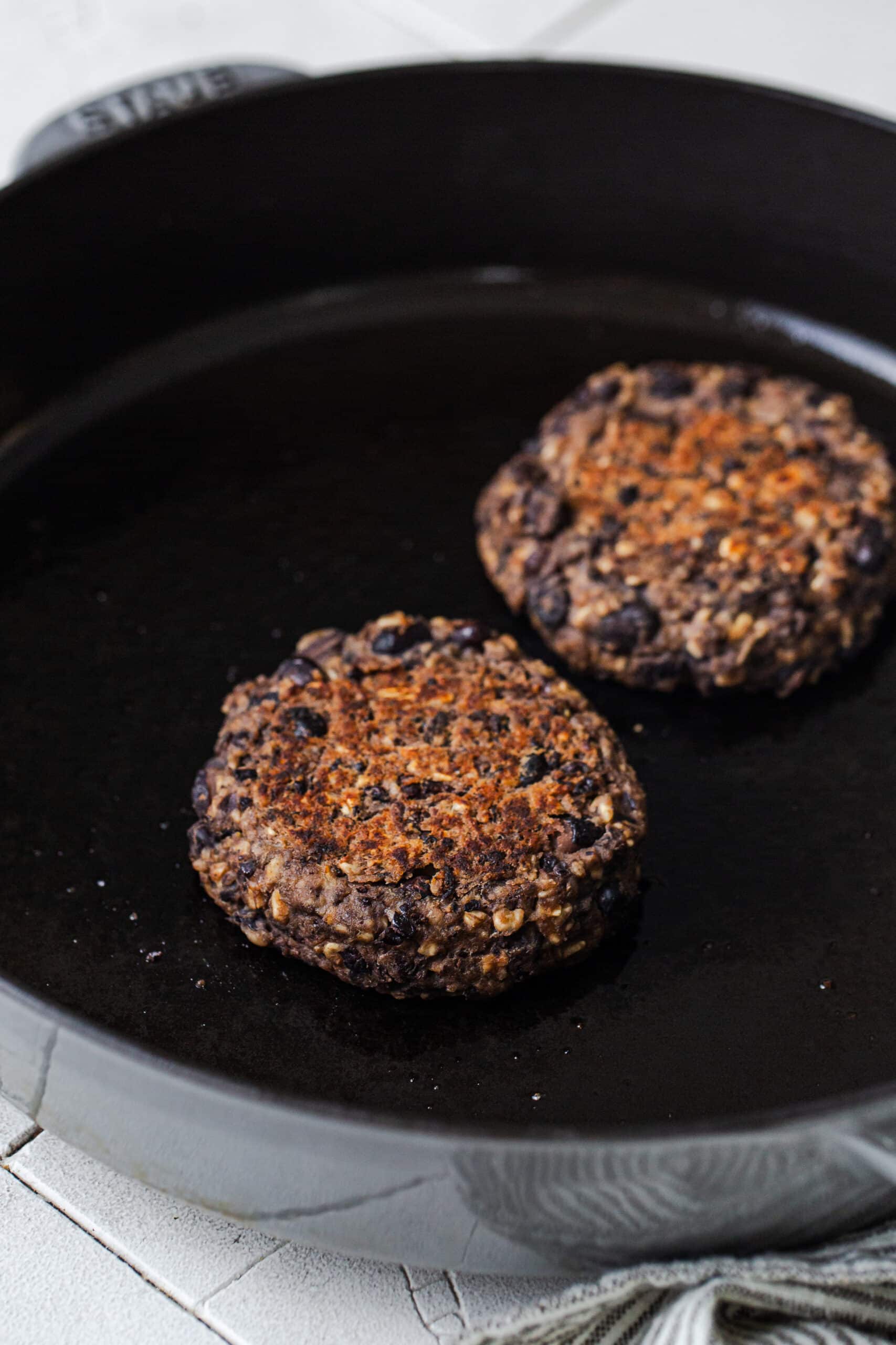black bean smash burgers cooking in a cast iron skillet