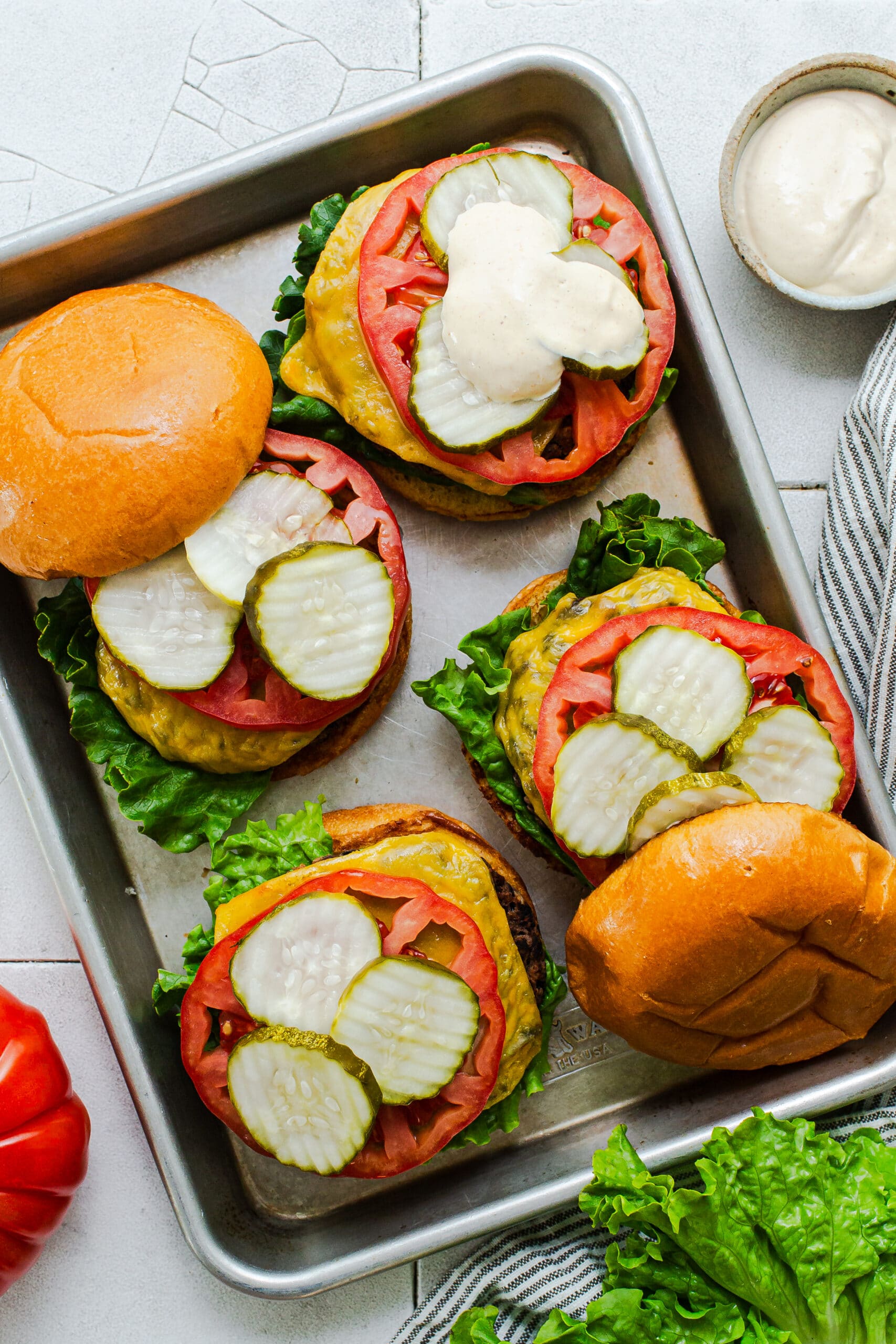 assembled burgers with toppings on a quarter sheet pan