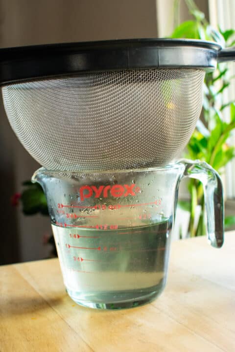 pouring syrup through a fine mesh strainer