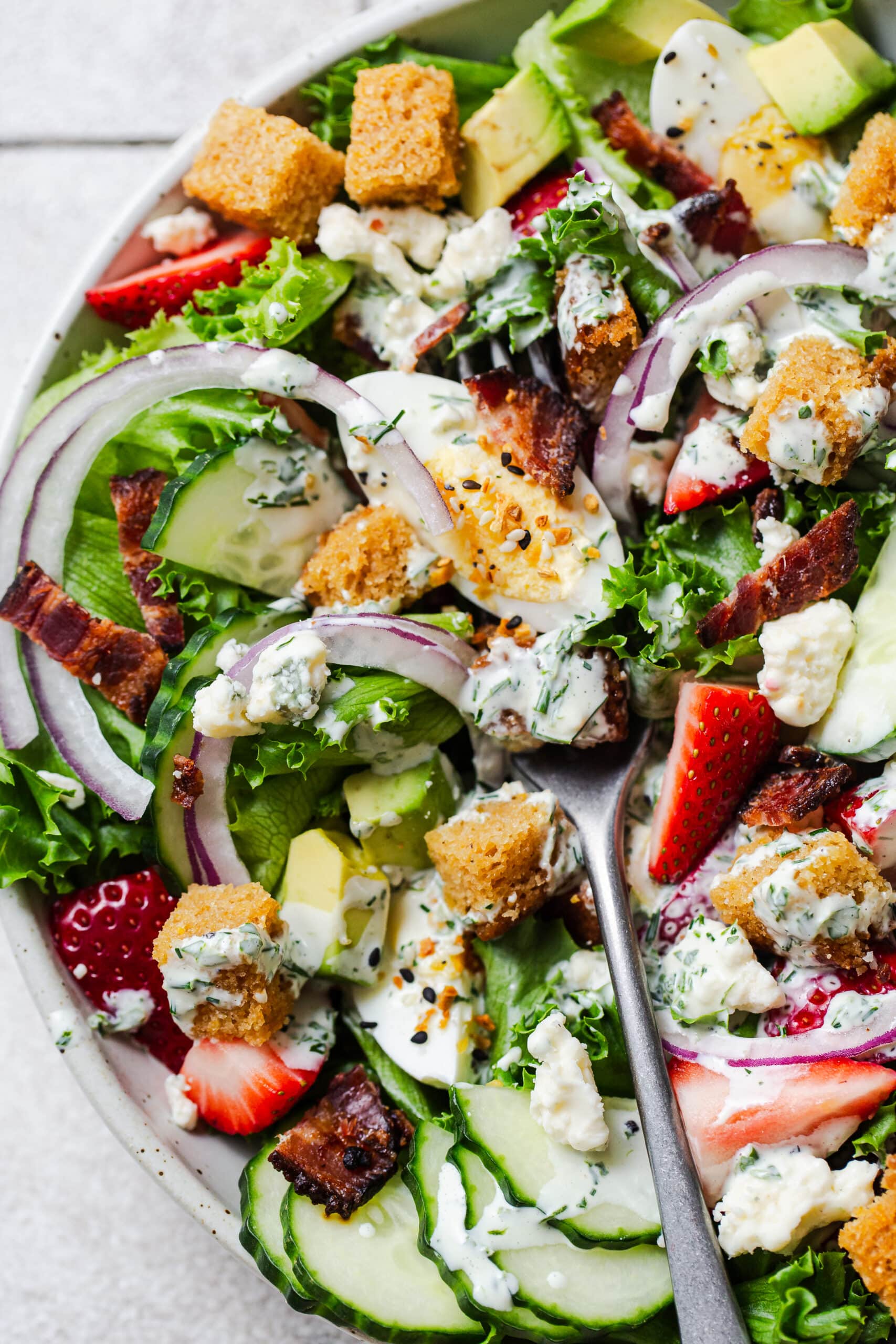 closeup of a salad with strawberries, bacon, cornbread croutons