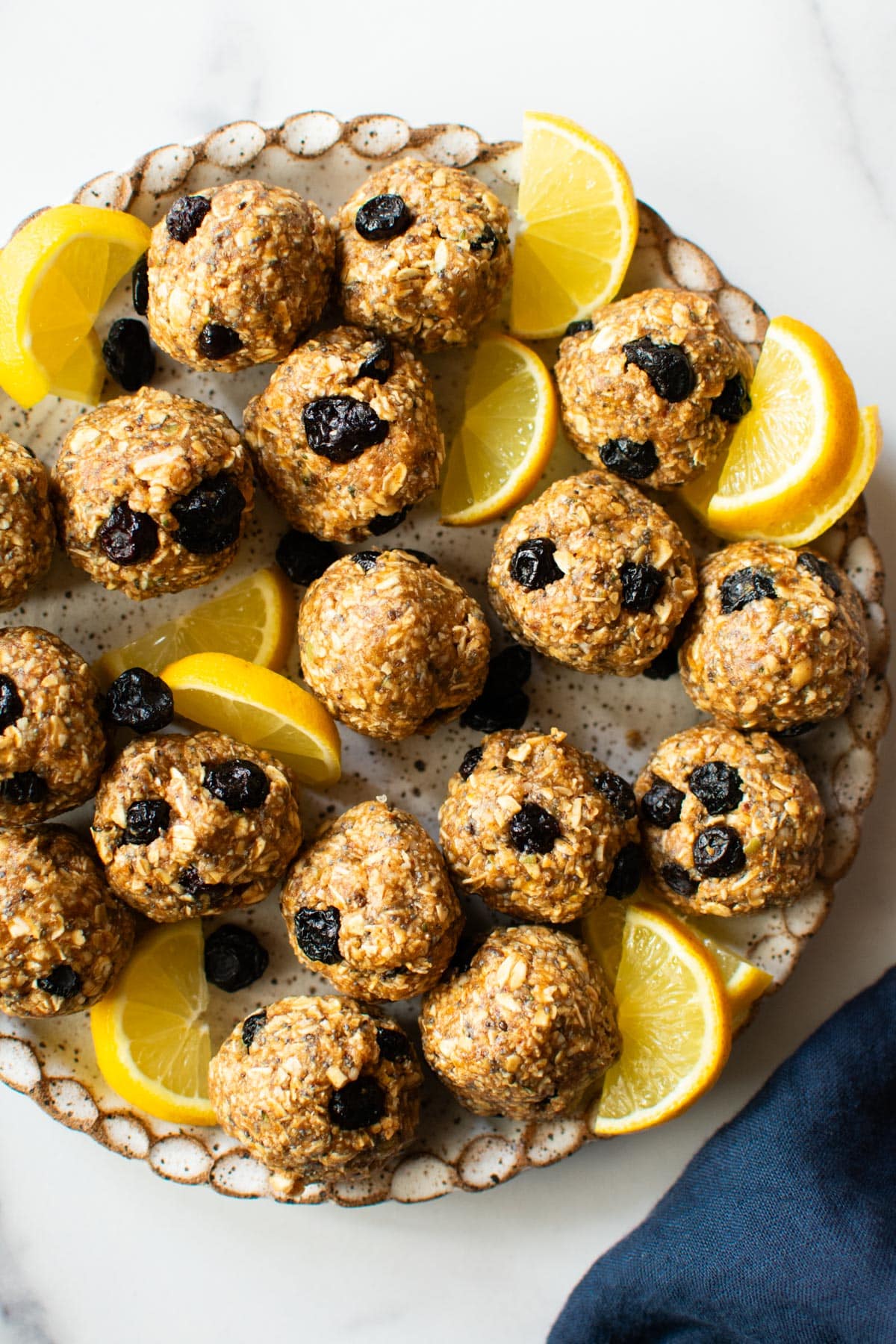 blueberry lemon no-bake oat bites on a plate with lemon wedges