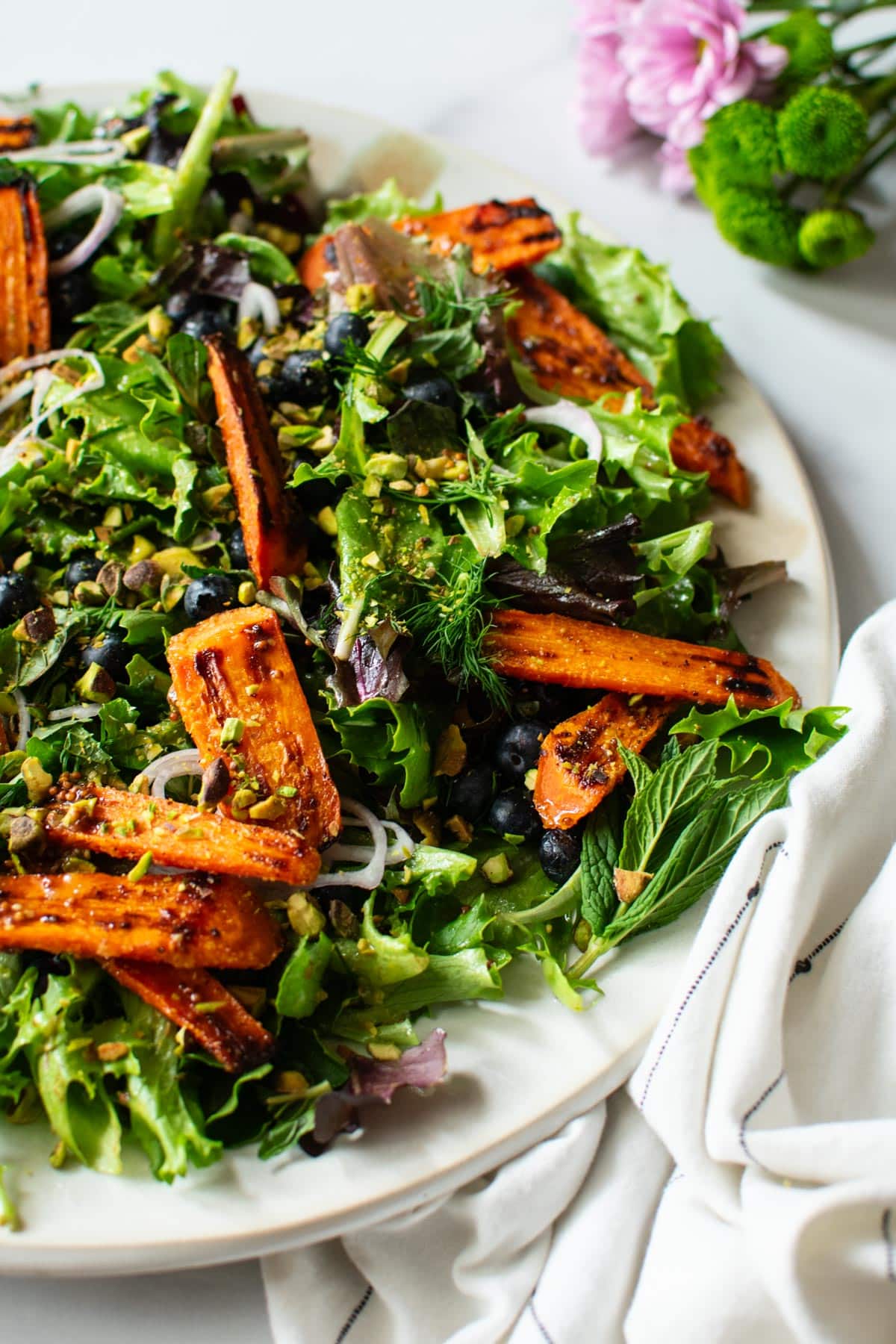 closeup of a spring salad with roasted carrots and pistachios and blueberries