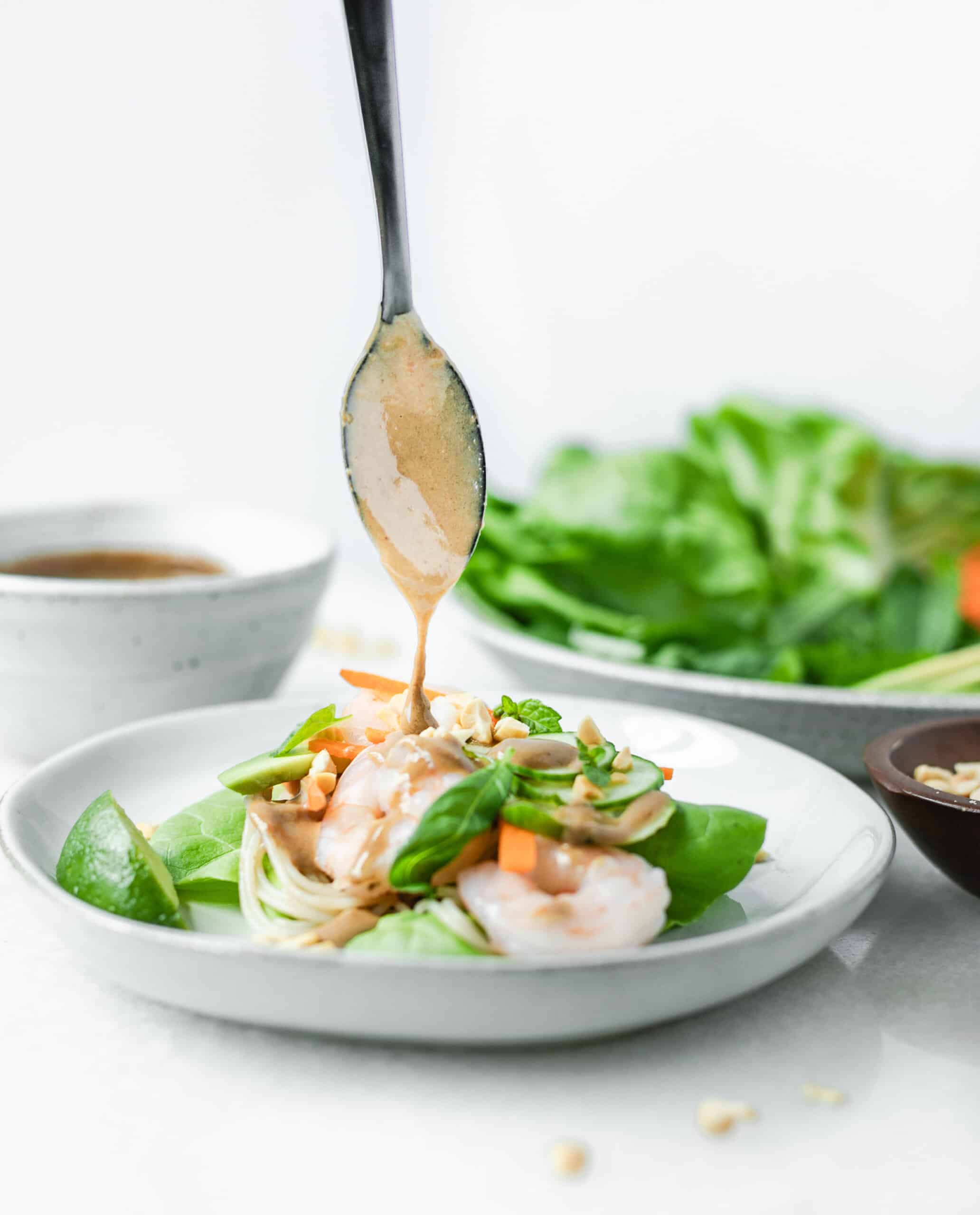 spoonful of peanut sauce getting drizzled on a shrimp lettuce wrap
