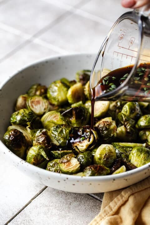 pouring sauce on roasted brussels sprouts