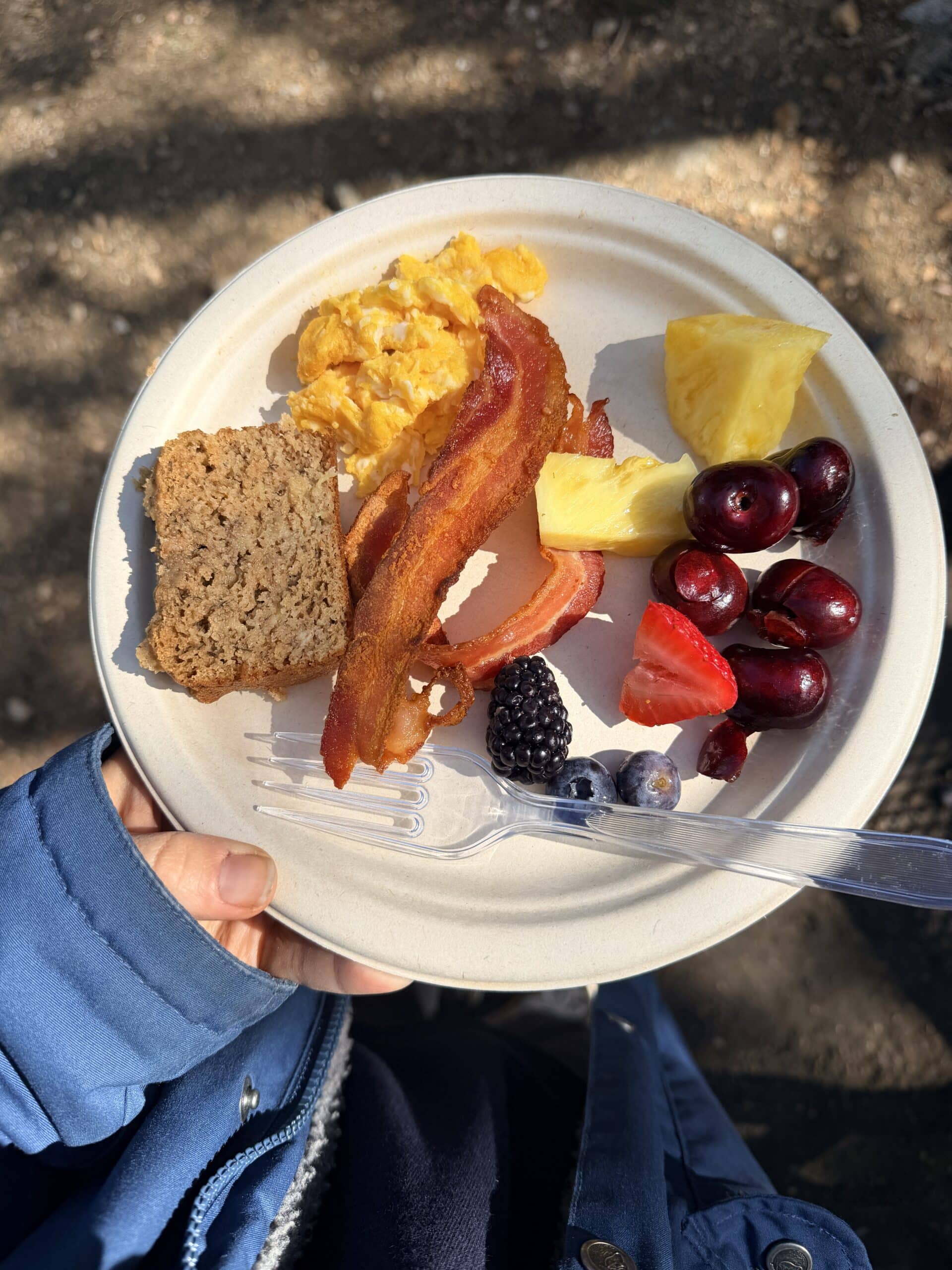 breakfast plate with eggs, bacon, fruit and banana bread