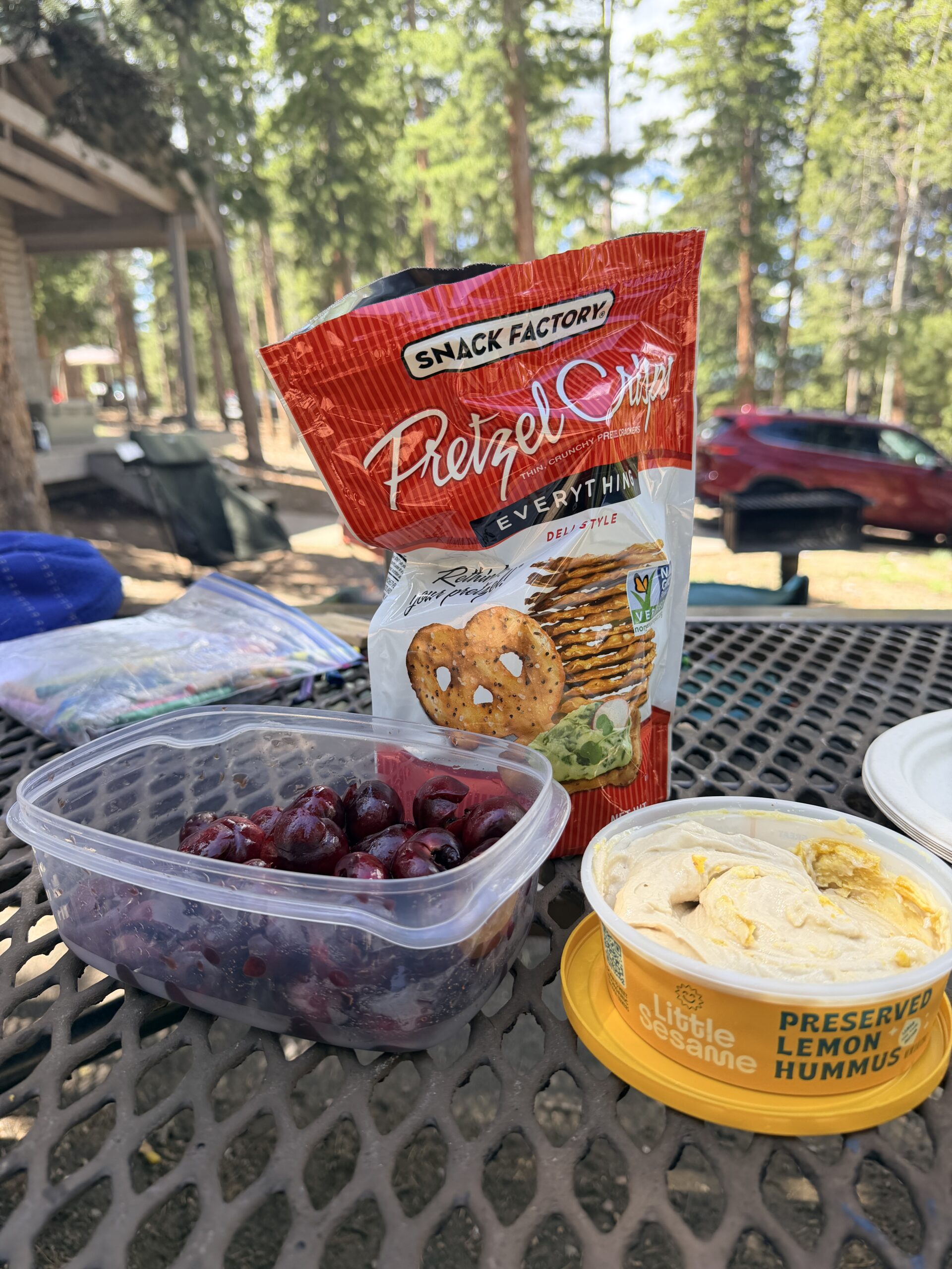 pretzel thins, hummus and cherries on a table