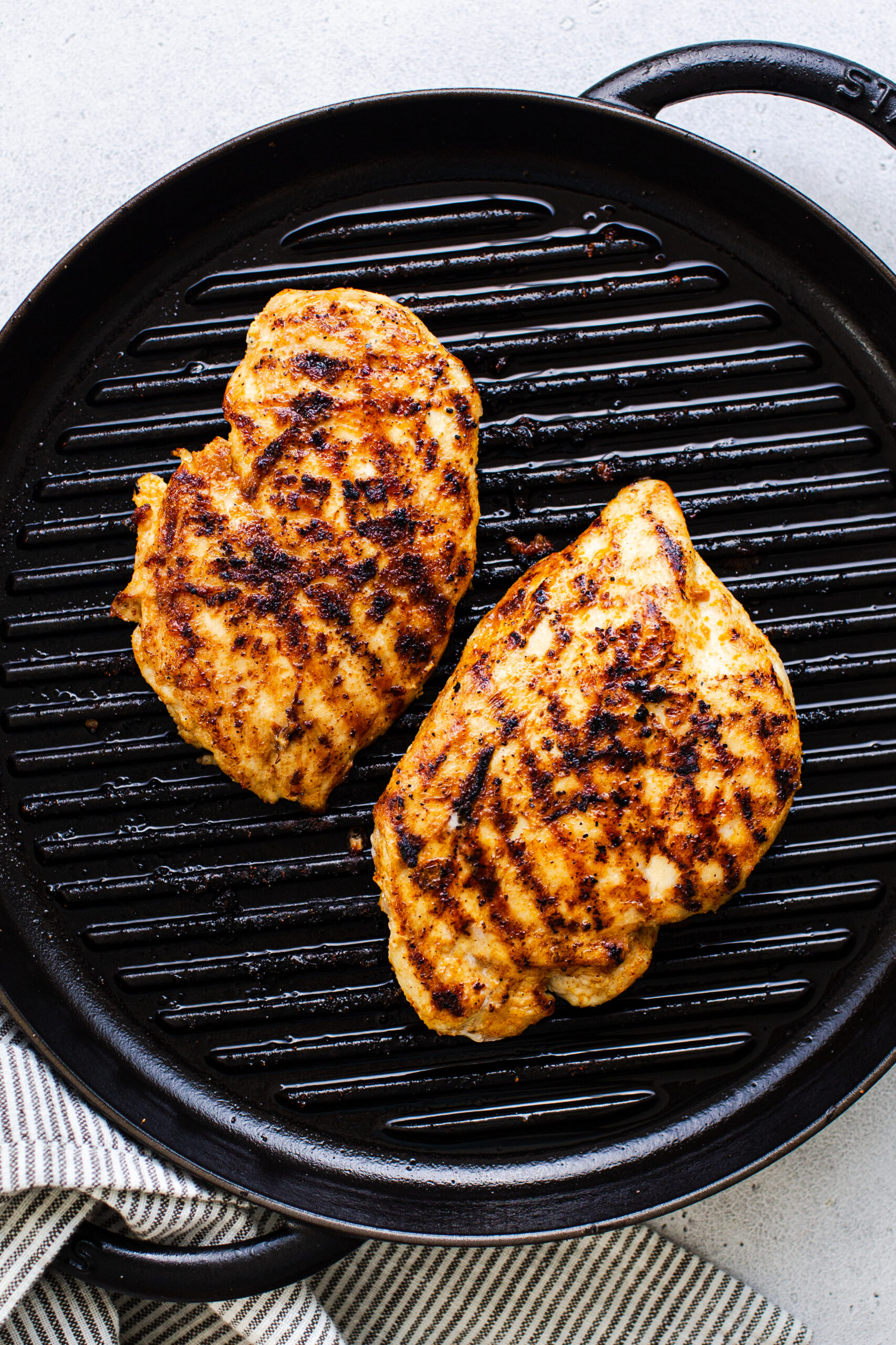two grilled chicken breasts on a grill pan