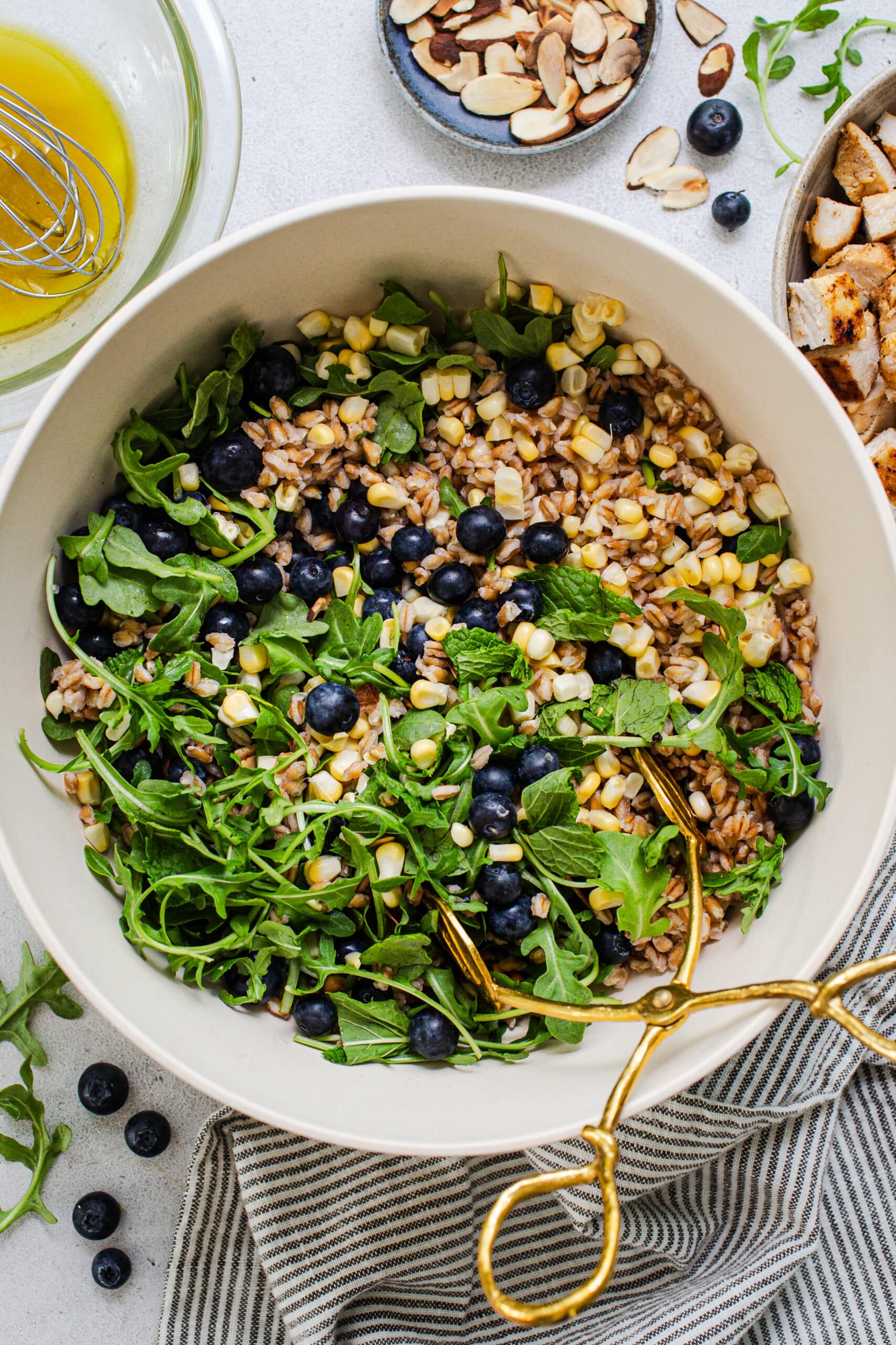 big bowl of healthy summer farro salad with gold tongs