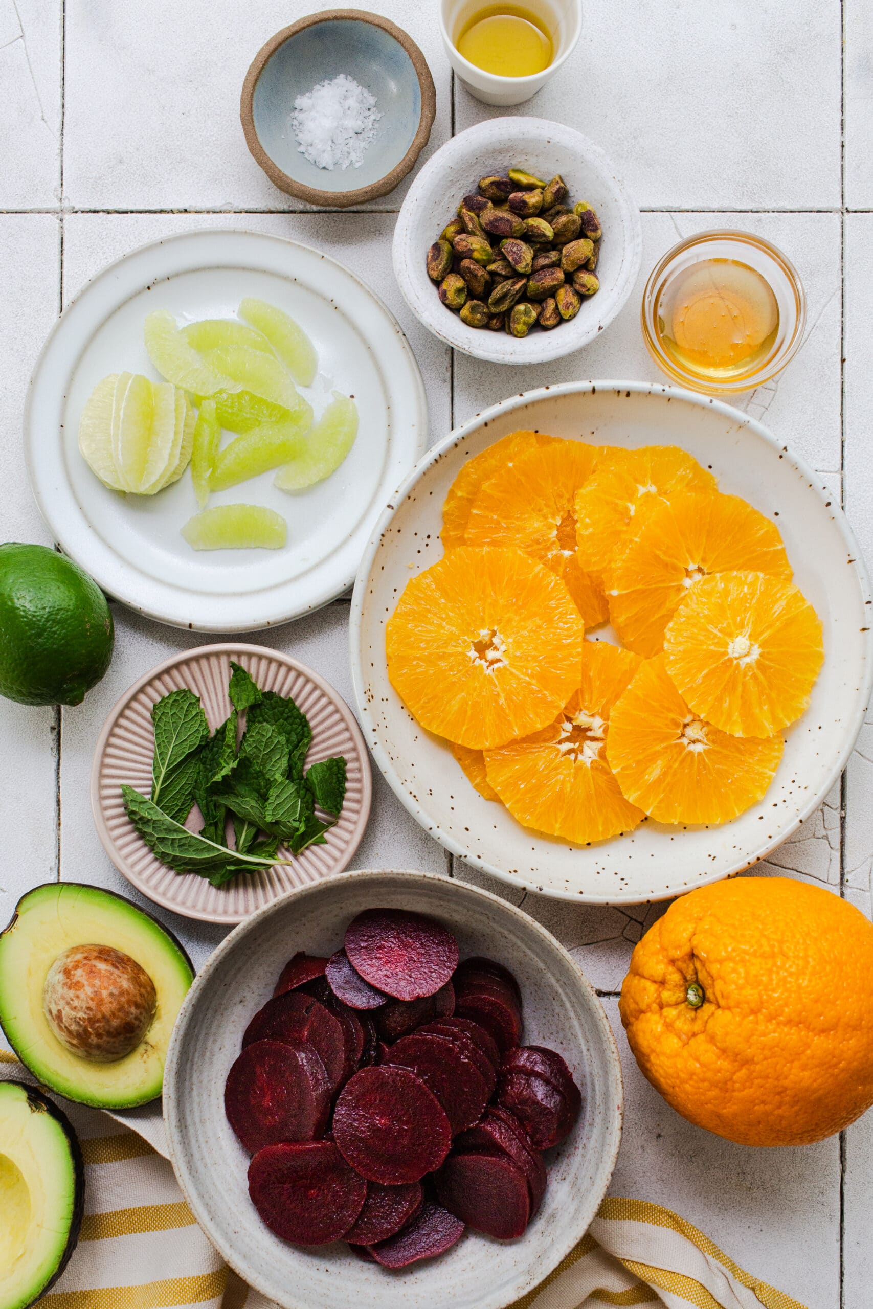 orange rounds, lime segments, mint leaves, pistachios, sliced beets on plates